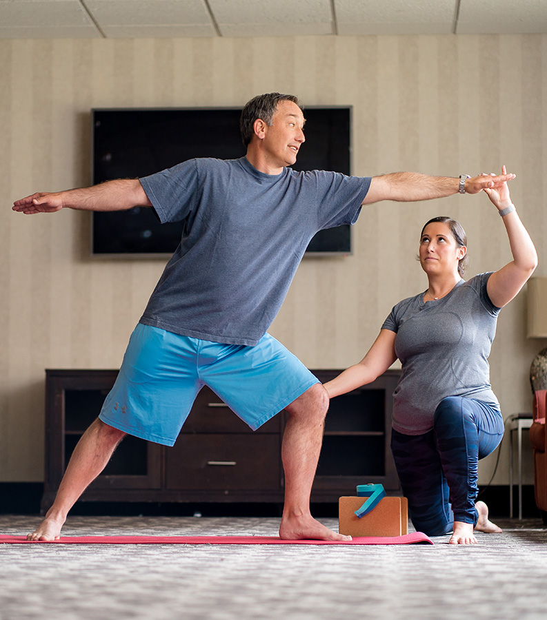Instructor guiding a student through a pose during a private yoga class at home